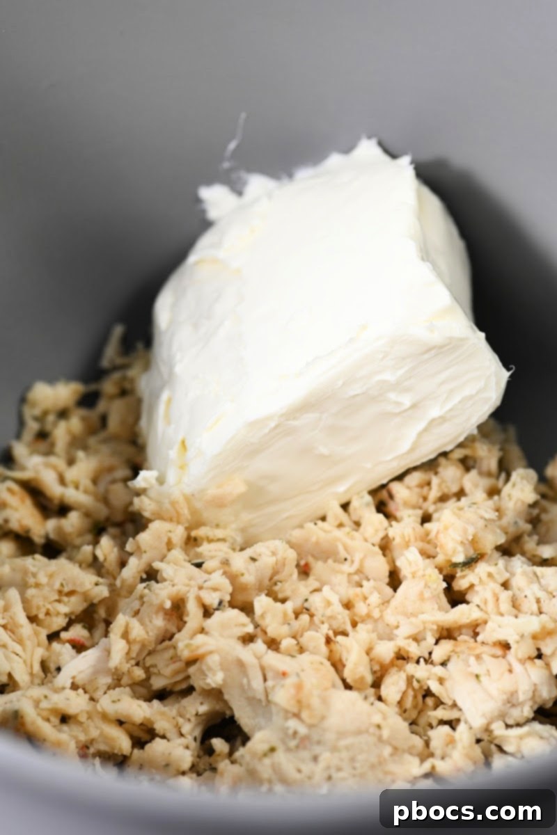 Adding cream cheese to shredded chicken
