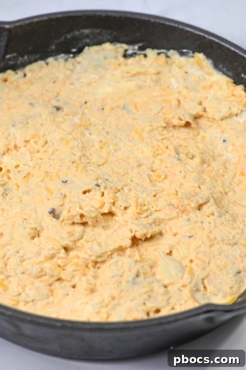 Spreading the uncooked buffalo dip in the skillet