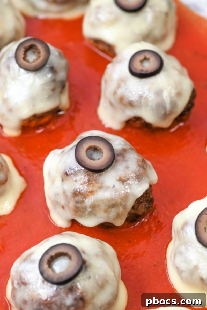 Meatballs with melted mozzarella cheese on top, ready for black olive irises