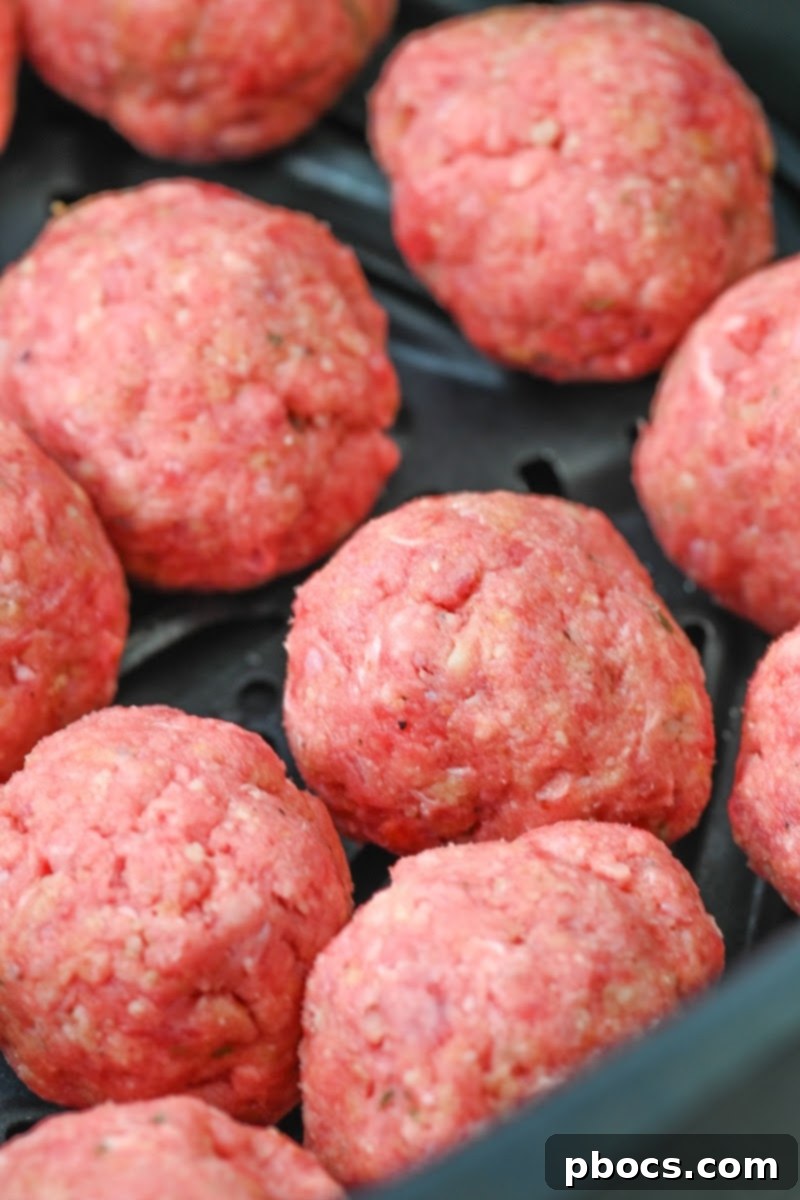 Raw meatballs placed in an air fryer basket, ready for cooking