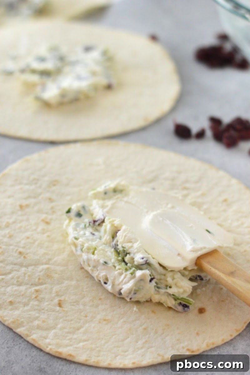 Spreading the cream cheese mixture evenly onto a keto tortilla.