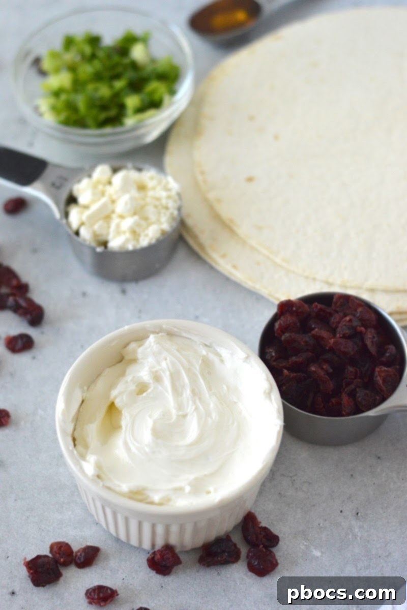 All ingredients laid out for Low-Carb Cranberry Cream Cheese Pinwheels: tortillas, cream cheese, feta, cranberries, green onions, and honey.