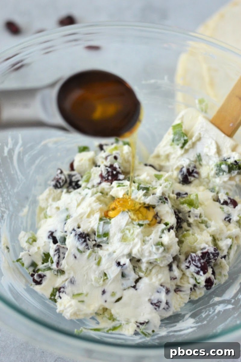 Adding sugar-free honey to the cream cheese mixture in a bowl.
