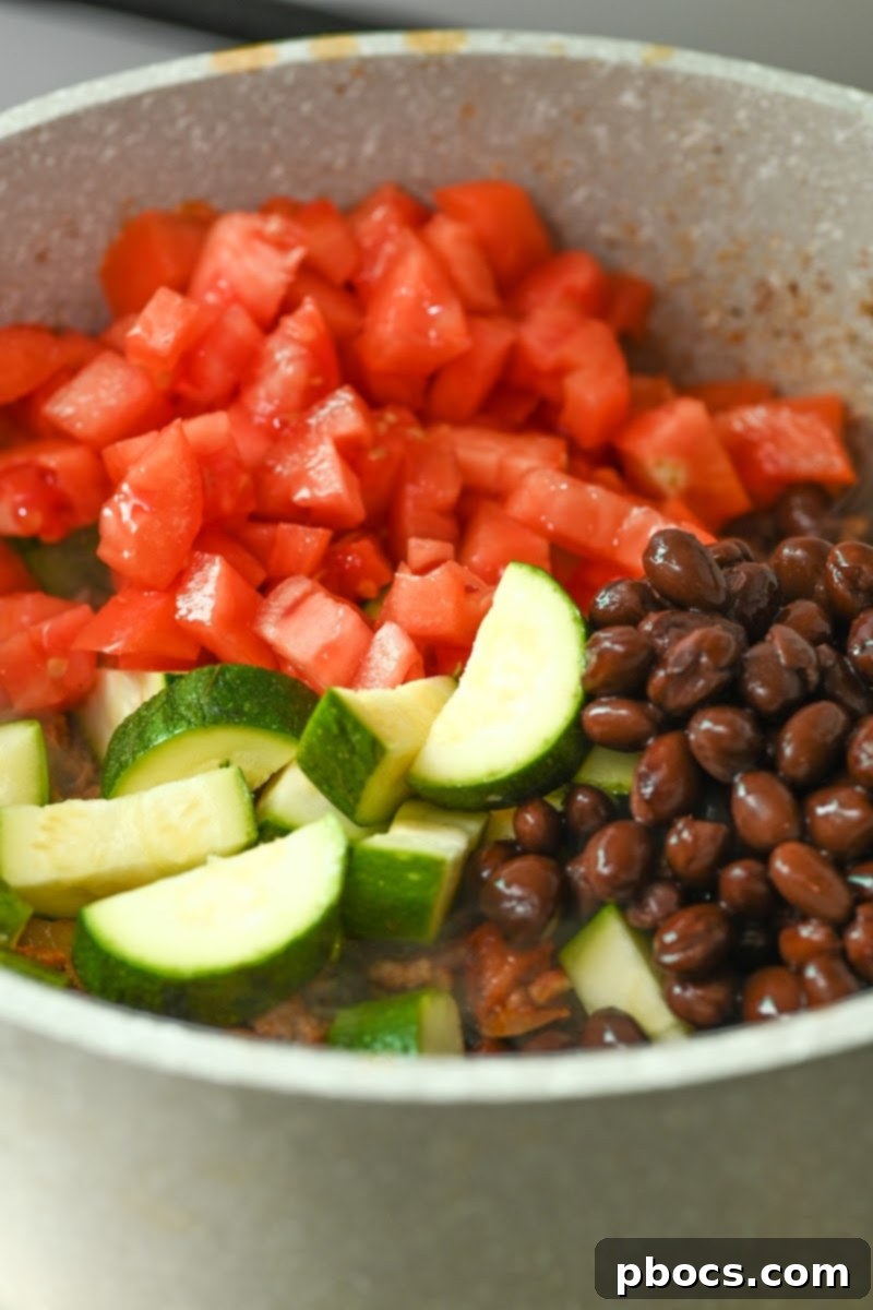 Adding tomatoes, black soybeans, and zucchini to chili base