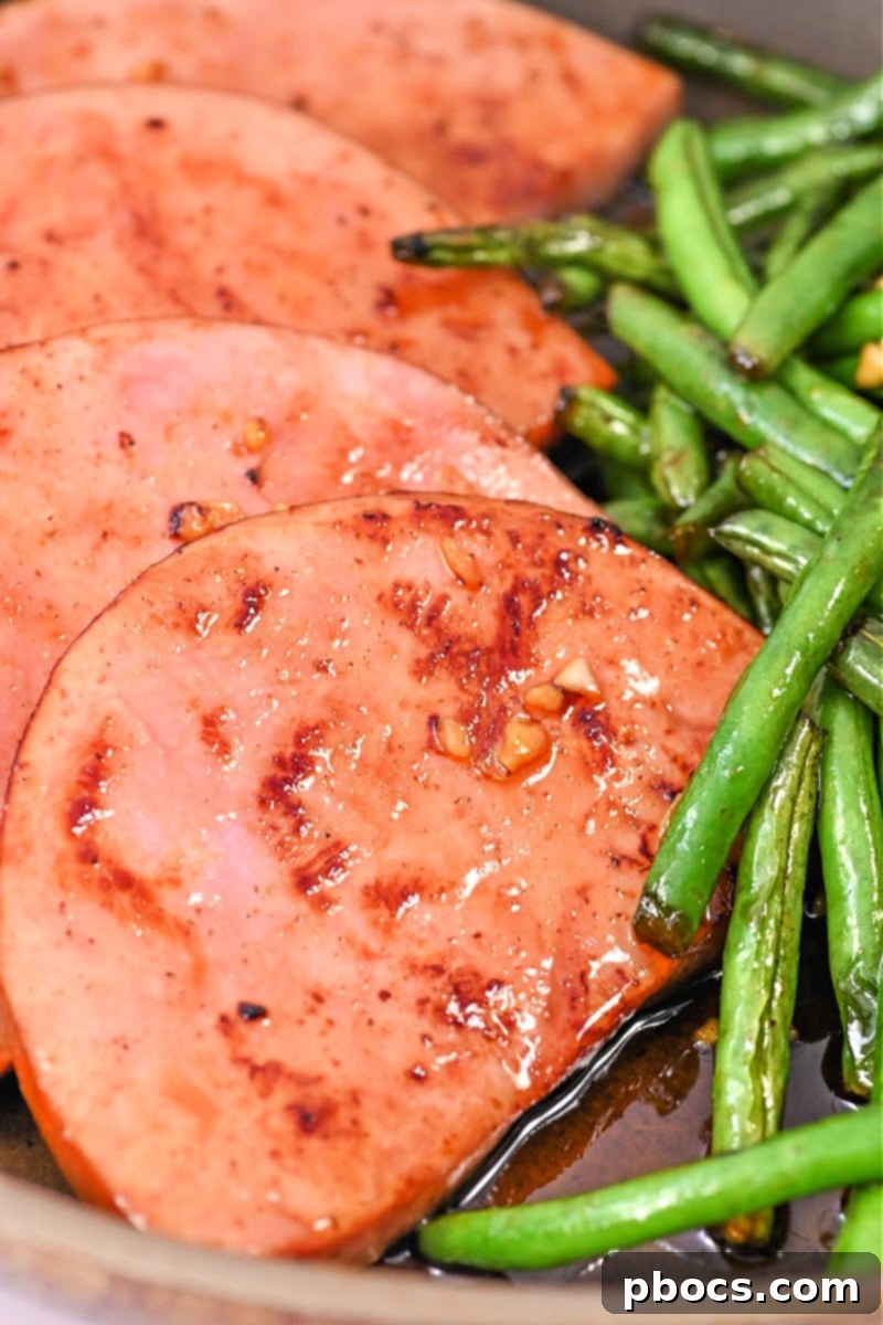 One-Pan Keto Honey-Glazed Ham and Green Beans 5 Close-up of cooked ham and green beans in a skillet, coated in a glistening glaze