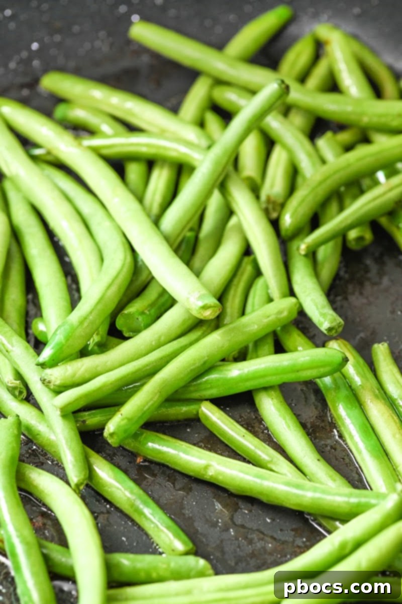 One-Pan Keto Honey-Glazed Ham and Green Beans 10 Green beans cooking in a skillet with spices