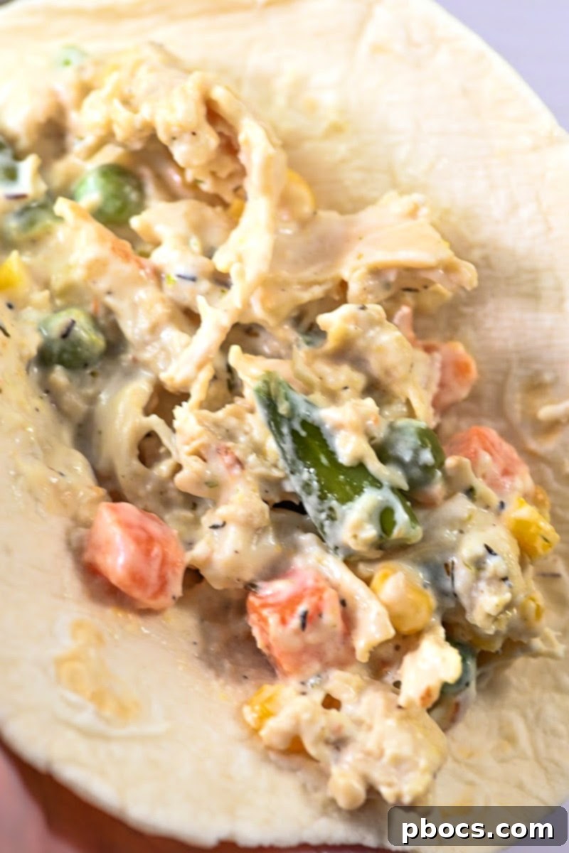 Carefully filling a low-carb tortilla with the creamy chicken pot pie mixture.