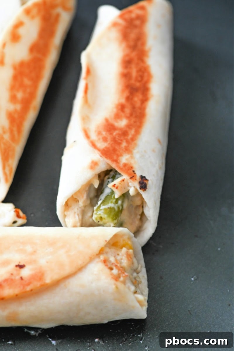 Frying the chicken pot pie roll-ups in a skillet until golden brown and crispy.