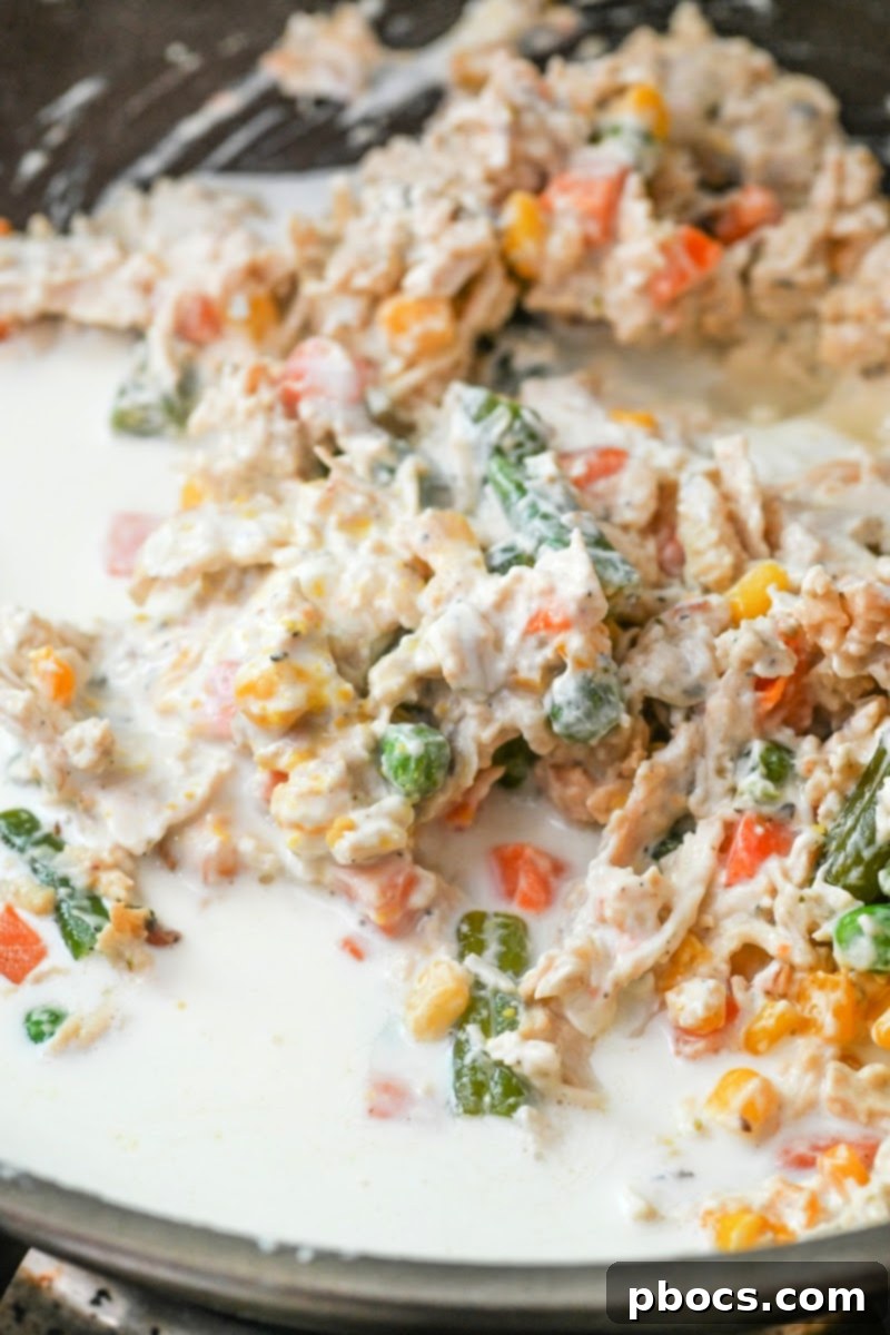 Cooking the creamy chicken and vegetable mixture in a skillet until thickened.
