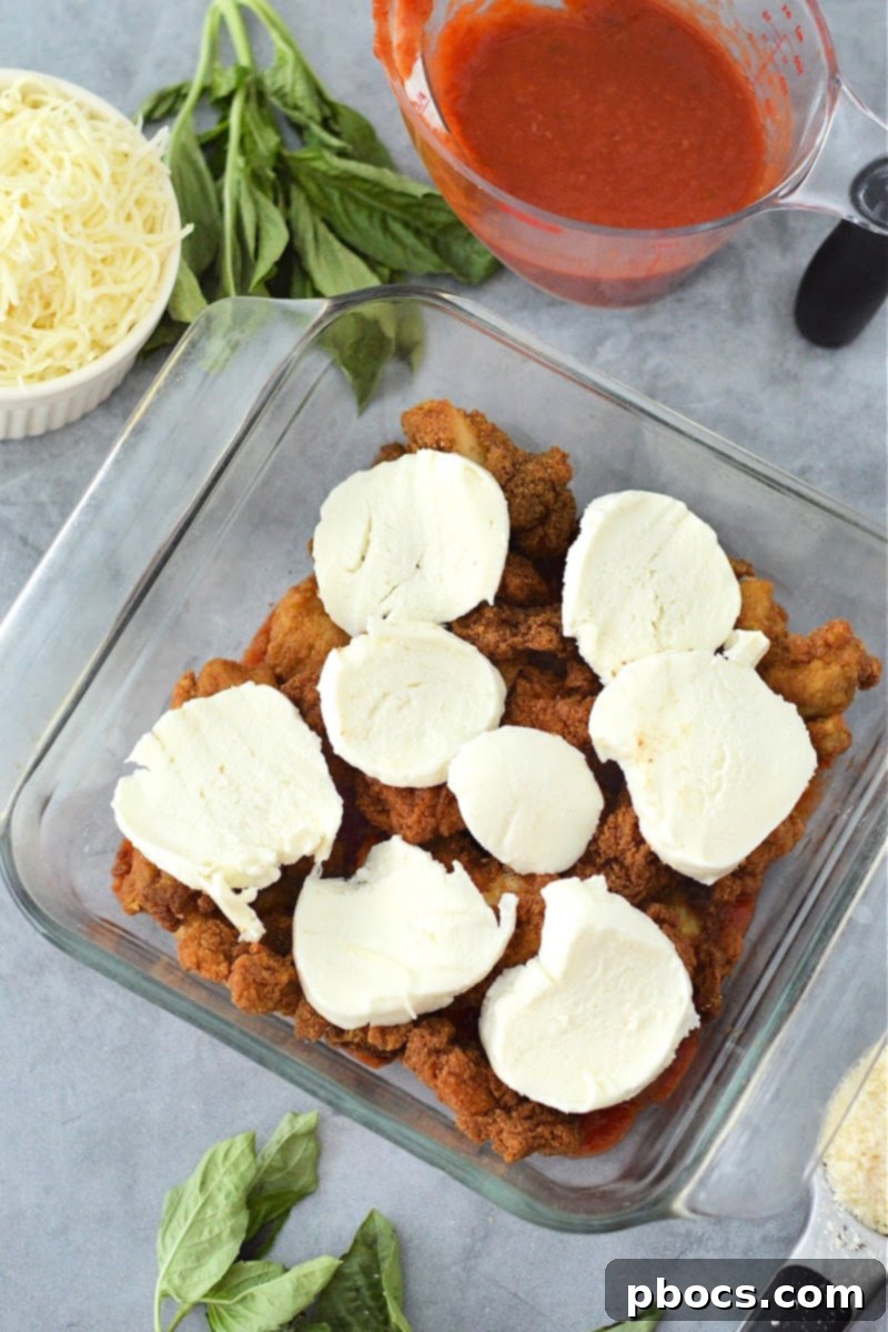 Keto Chicken Parmesan Nugget Bake 11 Slices of fresh mozzarella being layered on top of chicken nuggets