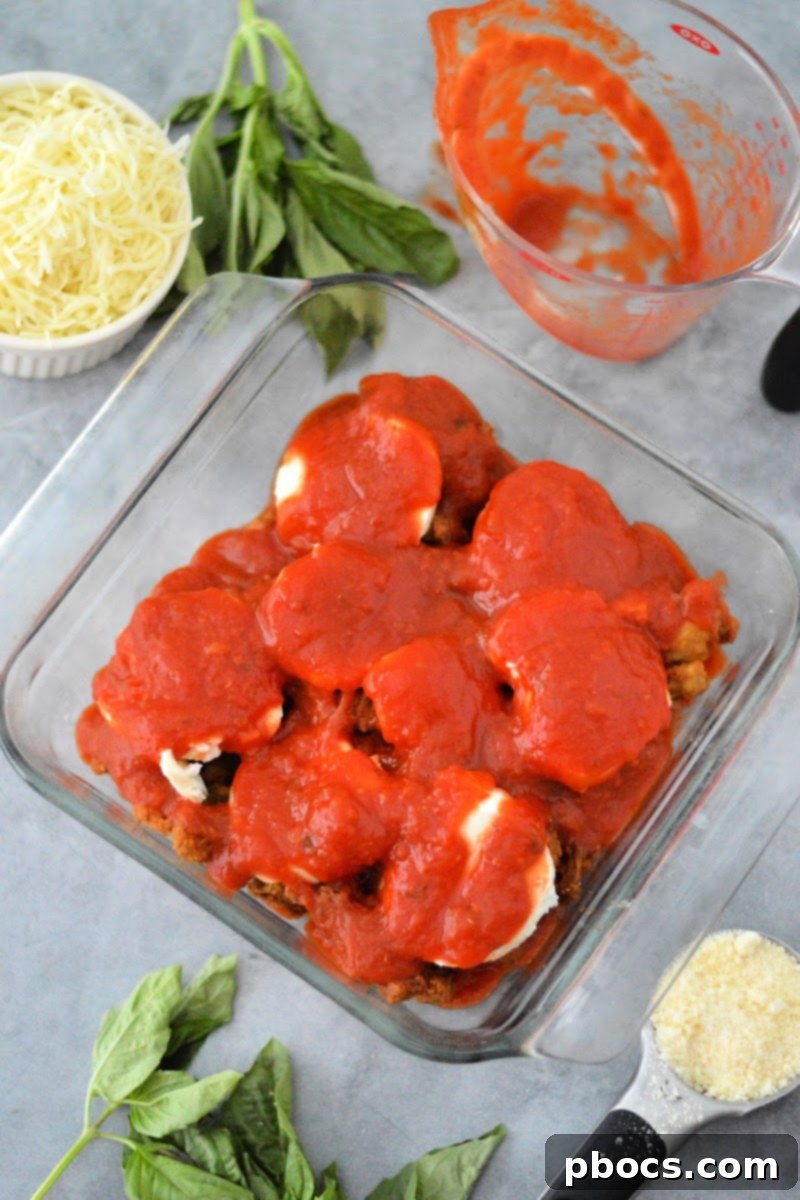 Keto Chicken Parmesan Nugget Bake 12 Remaining marinara sauce being spooned over mozzarella and chicken nuggets