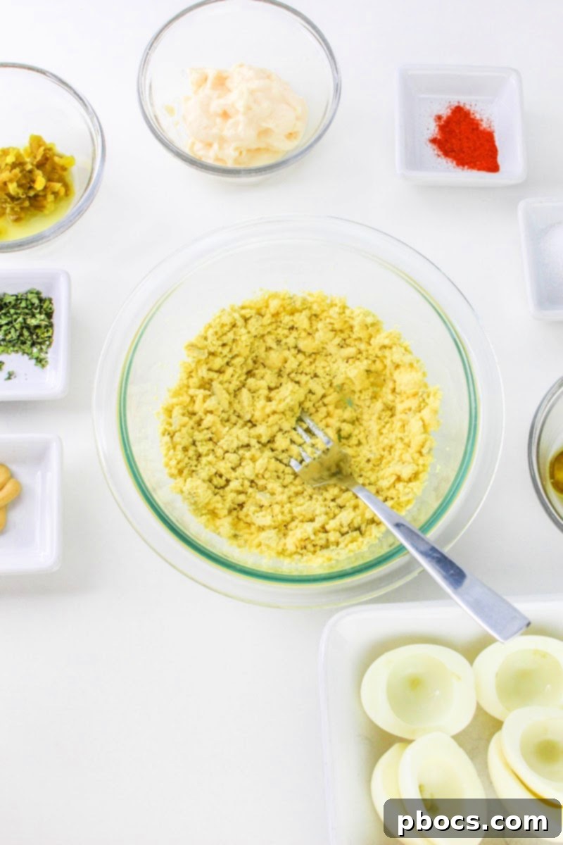 Mashing hard boiled egg yolks for deviled egg filling
