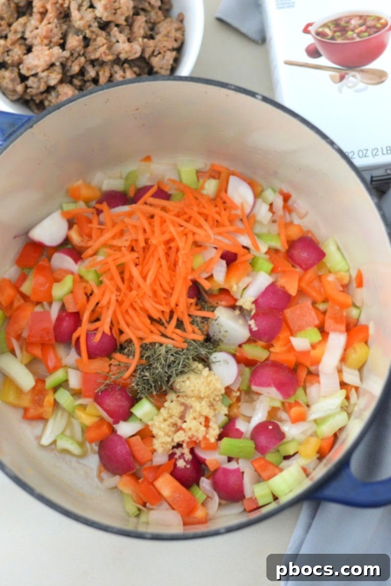 Carrots, spices, and garlic being added to softened vegetables in a pot