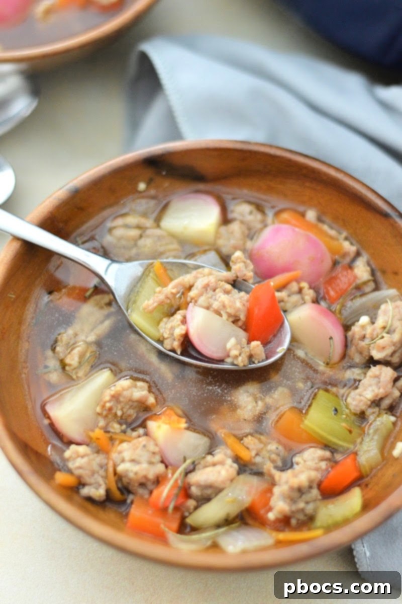 Close-up of a bowl of Keto Sausage and Veggie Soup with fresh herbs