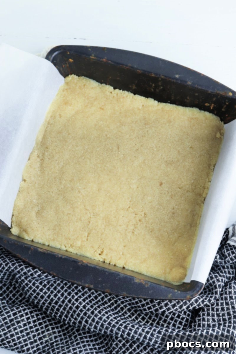 Low-Carb Turtle Pumpkin Cheesecake Bars - Pressing crust into dish