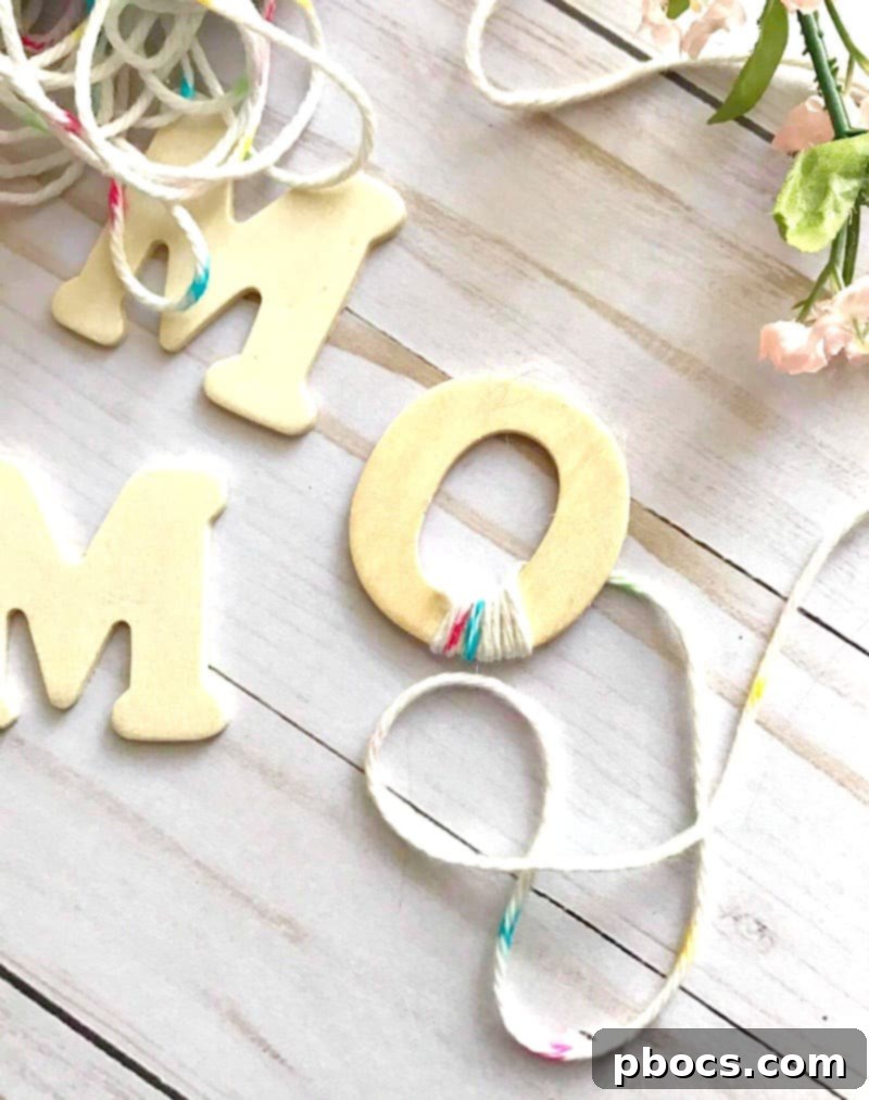 Finishing the yarn wrapping on a wooden letter by securing the end with glue