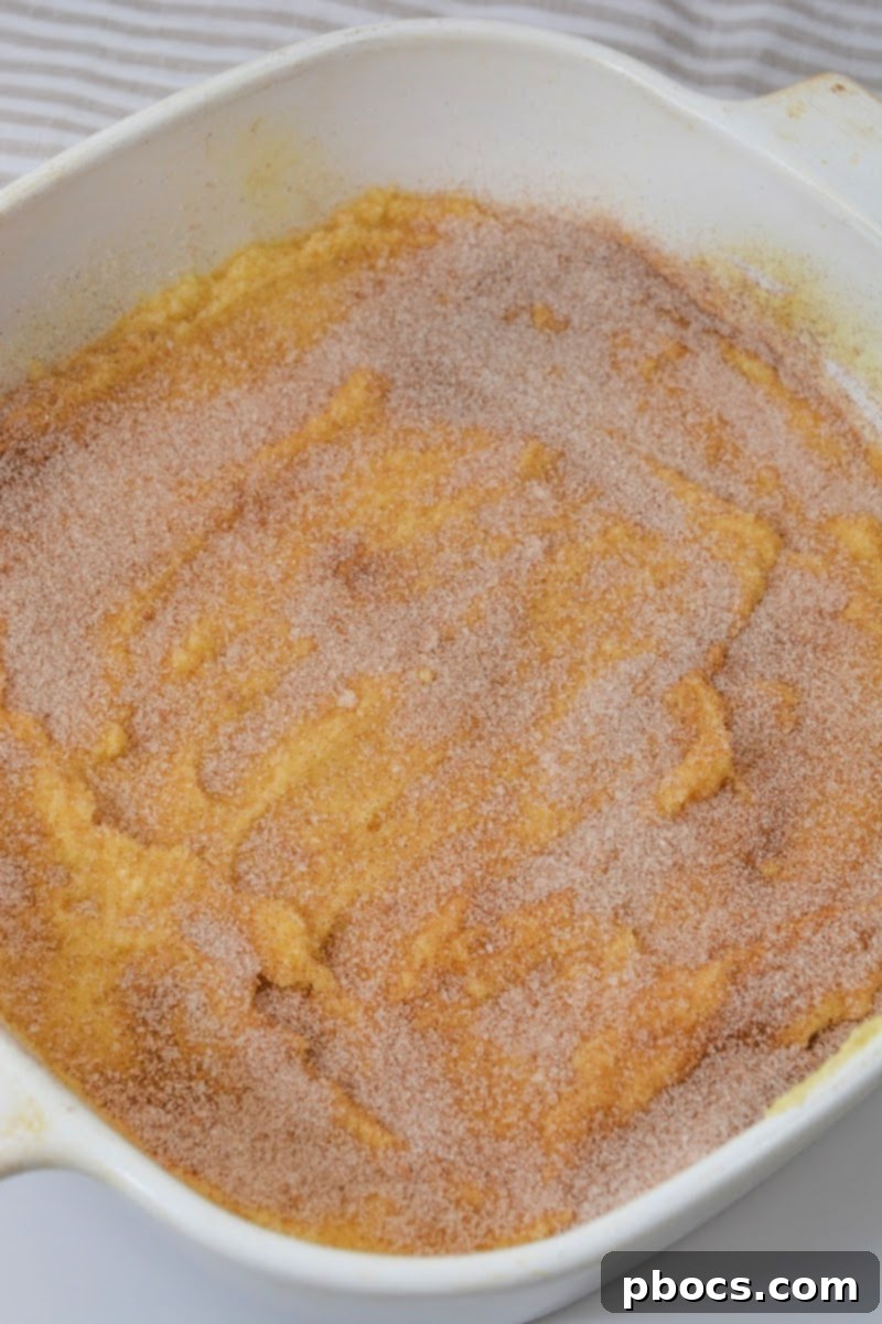 Sprinkling the cinnamon sugar mixture over the snickerdoodle batter in the baking dish.