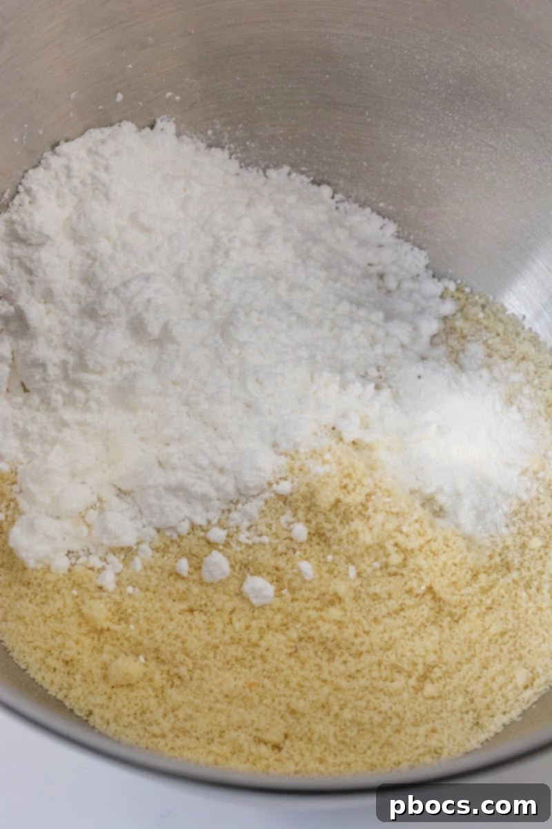 Mixing almond flour, baking powder, Swerve, eggs, vanilla, butter, and xanthan gum in a bowl.