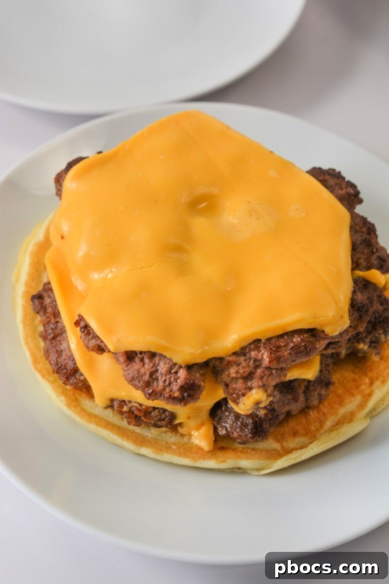 Placing cheesy smashburger patties on a keto pancake