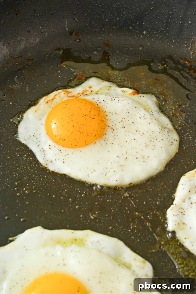 Frying eggs in a skillet for breakfast smashburgers
