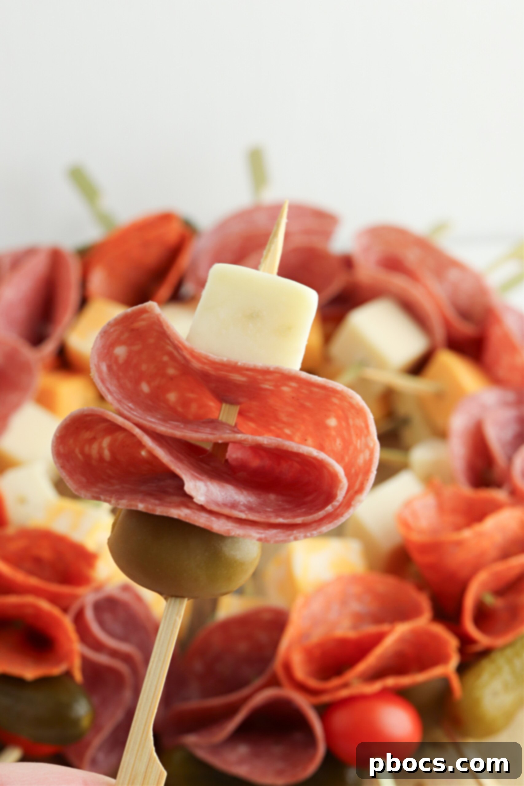 Layering a toothpick with an olive, meat and cheese
