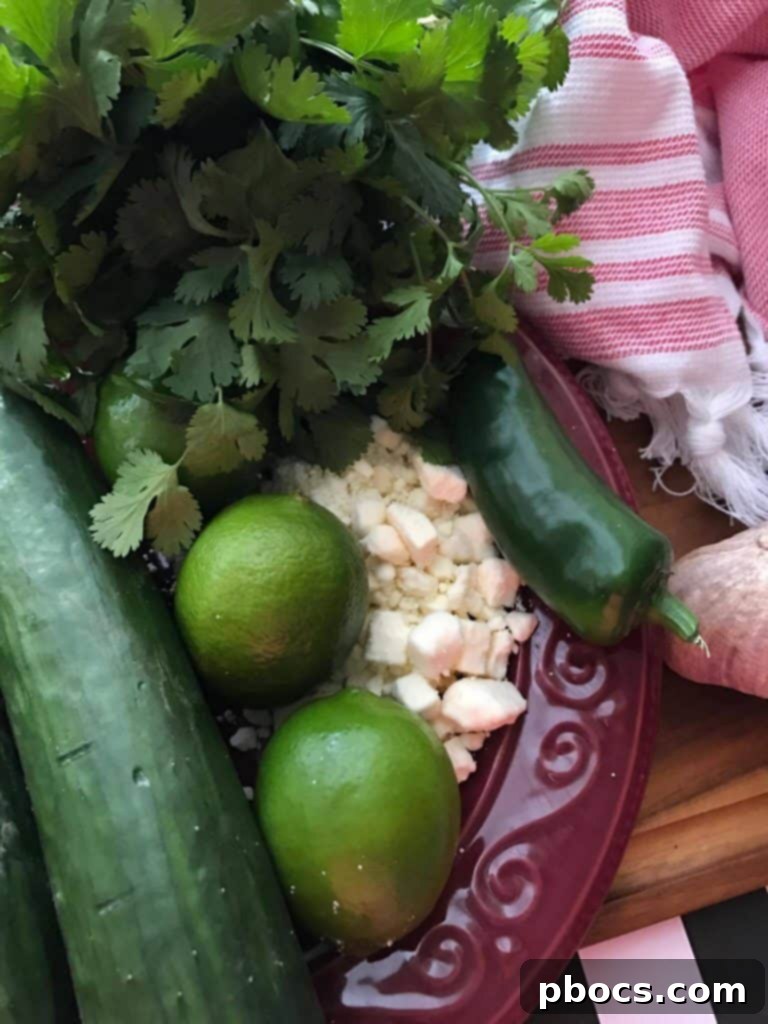 Crisp Cucumber Zesty Feta Jalapeno Kick Salad 3 Fresh ingredients laid out on a wooden board, including cucumbers, red pepper, jalapeño, cilantro, and limes, ready for the salad preparation.