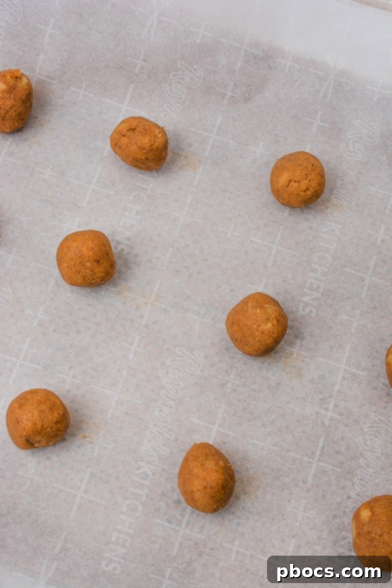 Hands rolling chilled cookie dough into small, uniform balls
