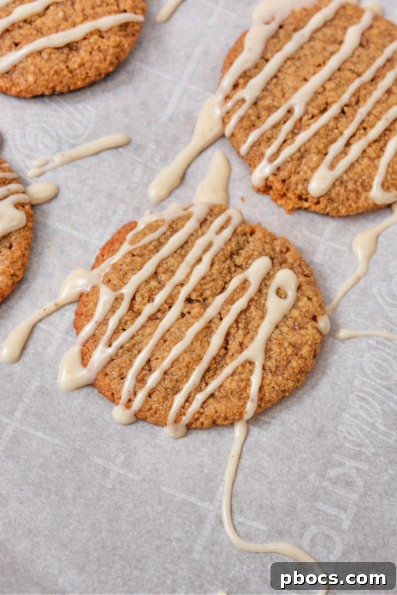 Hands carefully drizzling vanilla glaze over cooled Keto Gingerbread Latte Cookies