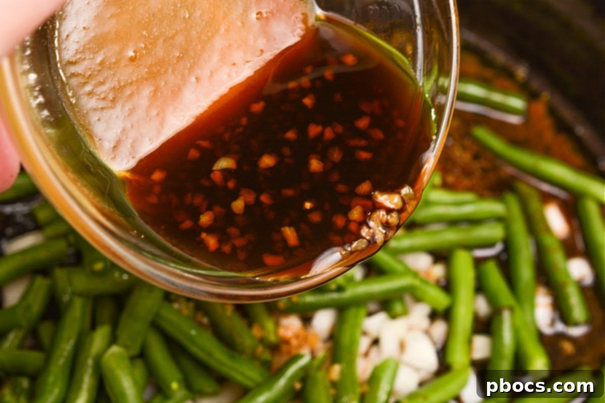One-Pan Low-Carb Crack Chicken with Green Beans 12 Pouring Asian-style sauce over green beans in a skillet