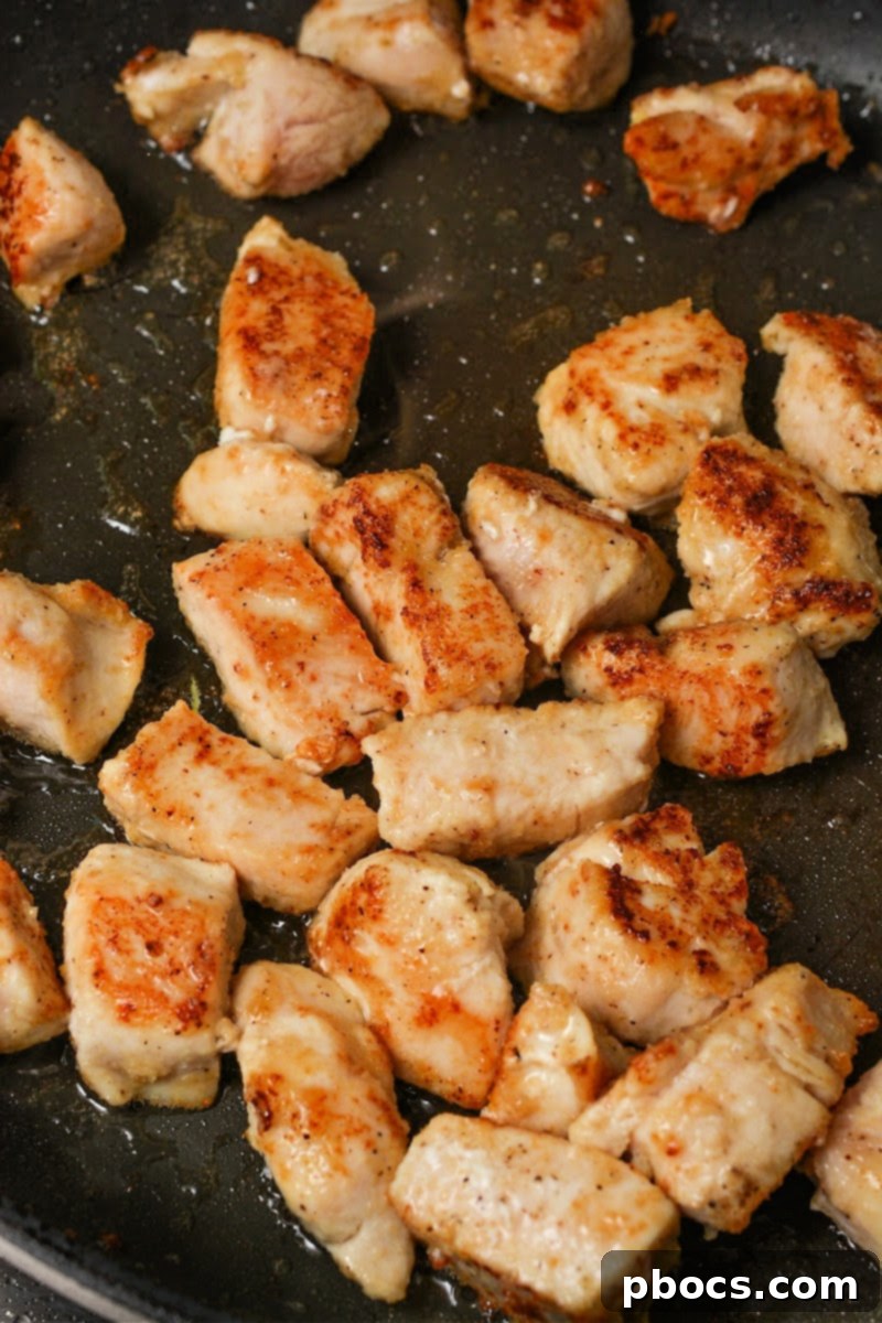 Seared chicken pieces in a hot skillet for Keto Skillet Honey Garlic Sausage and Chicken