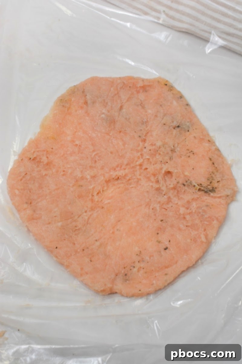 Keto Cheesy Ranch Chicken Pockets 11 Flattening a ball of seasoned ground chicken between two pieces of plastic wrap to form the hot pocket shell