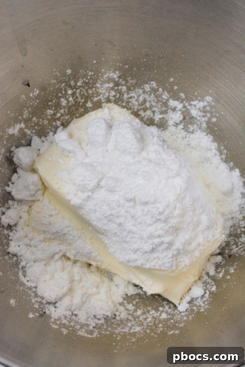 Cream cheese and Swerve confectioner's sugar substitute being blended in a mixing bowl until smooth