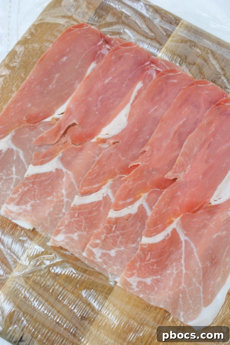 Laying out prosciutto slices on saran wrap for Italian sushi