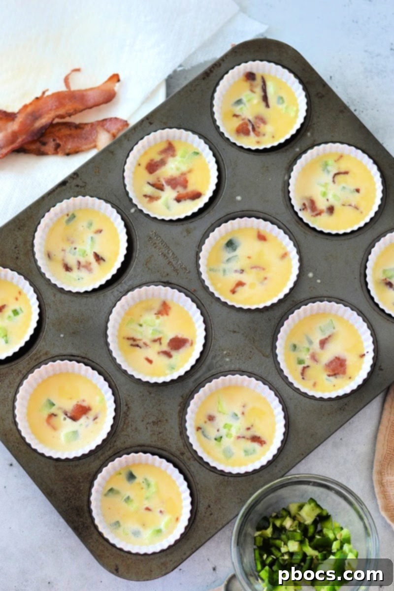 Unbaked Keto Jalapeno Popper Egg Bites with toppings added to the egg batter.