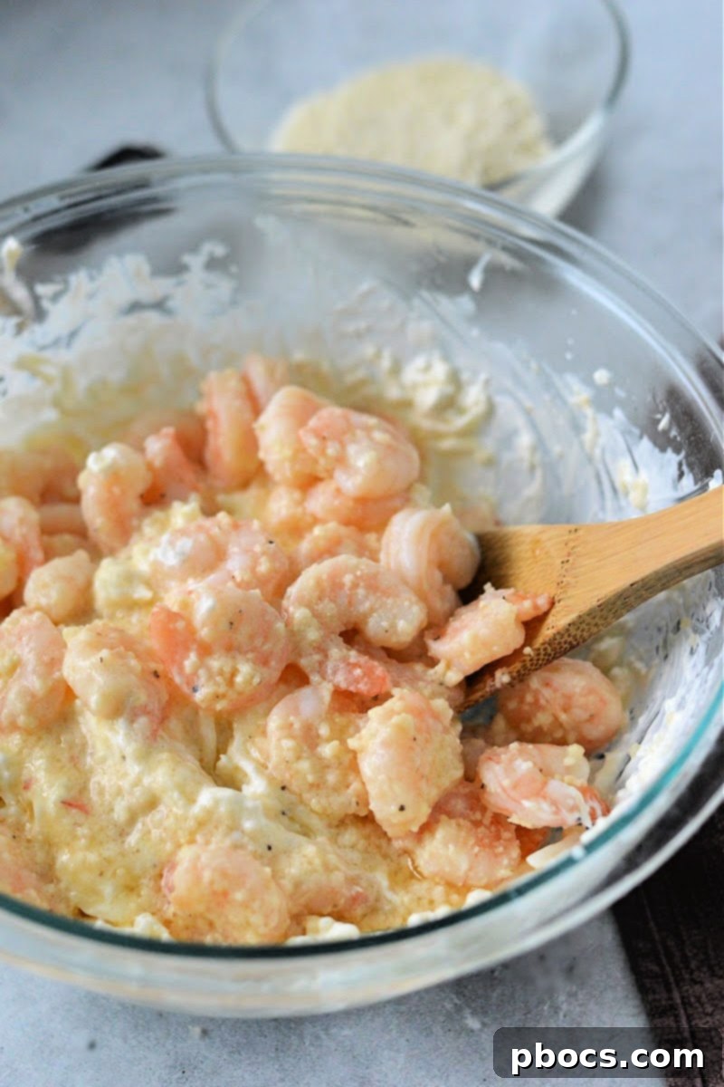 Cooked shrimp mixture being poured into the creamy cheese dip