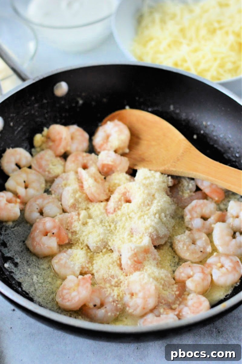 Adding grated Parmesan cheese to cooked shrimp in a skillet