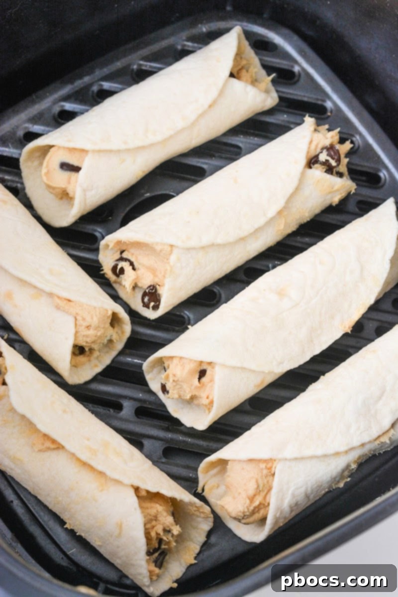 Unbaked peanut butter roll ups arranged in an air fryer basket
