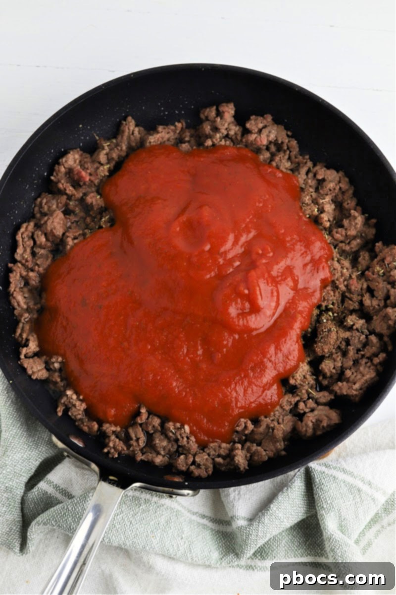 Adding marinara sauce to the ground beef mixture