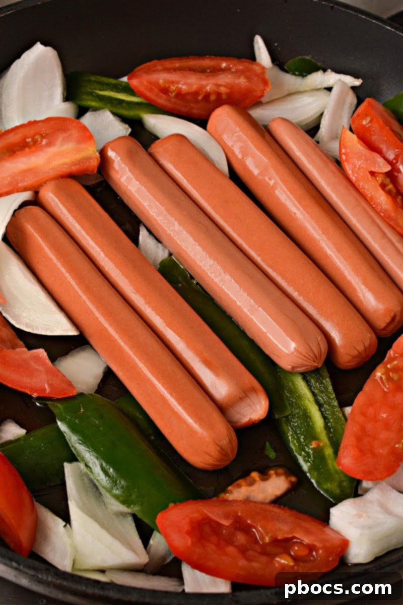 Cooking the hot dogs in the skillet with the veggies
