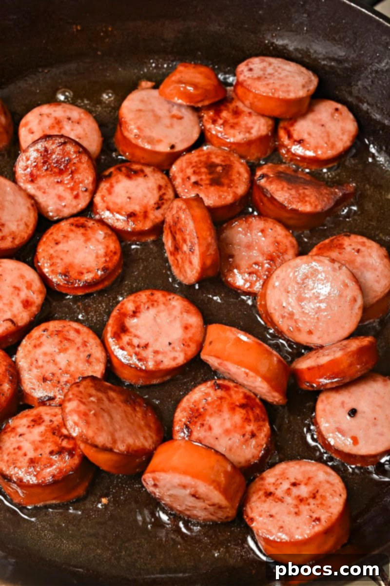 Sautéing kielbasa slices in a skillet until golden brown