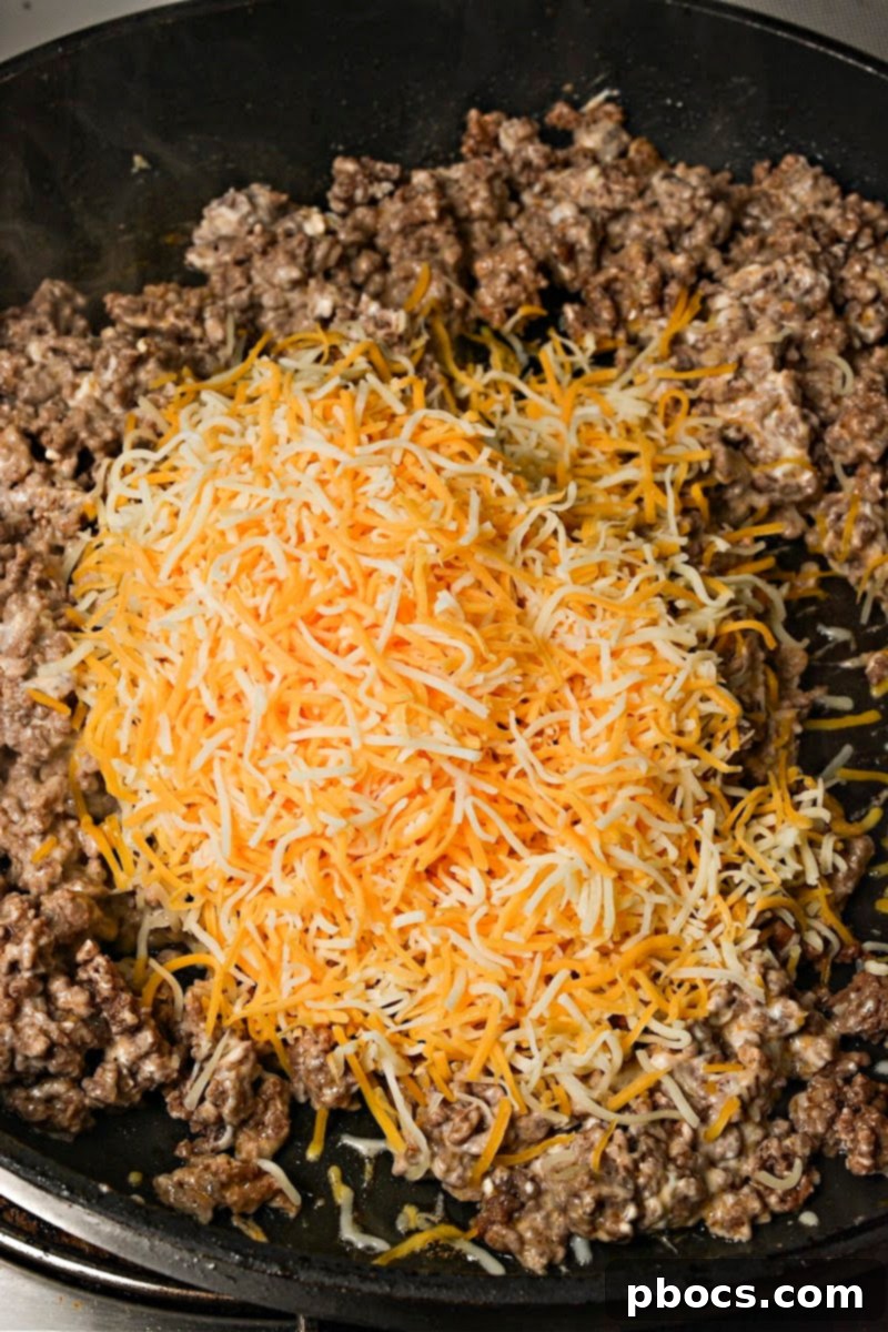 Keto Beef & Cheese Spirals 11 Adding shredded Colby Jack cheese to the ground beef and cream cheese mixture, stirring until melted