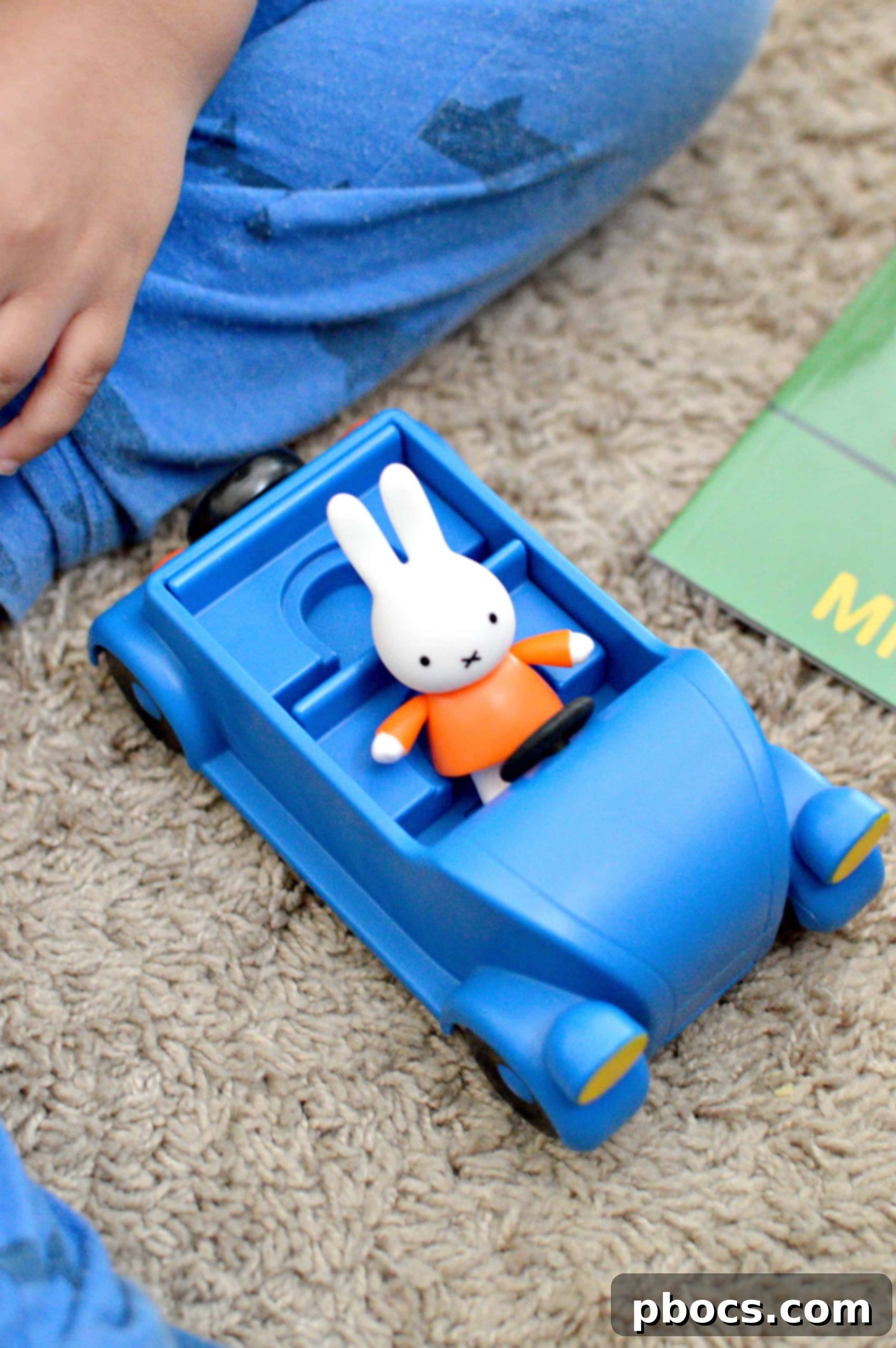 Child playing with Miffy car and small Miffy figure on a rug