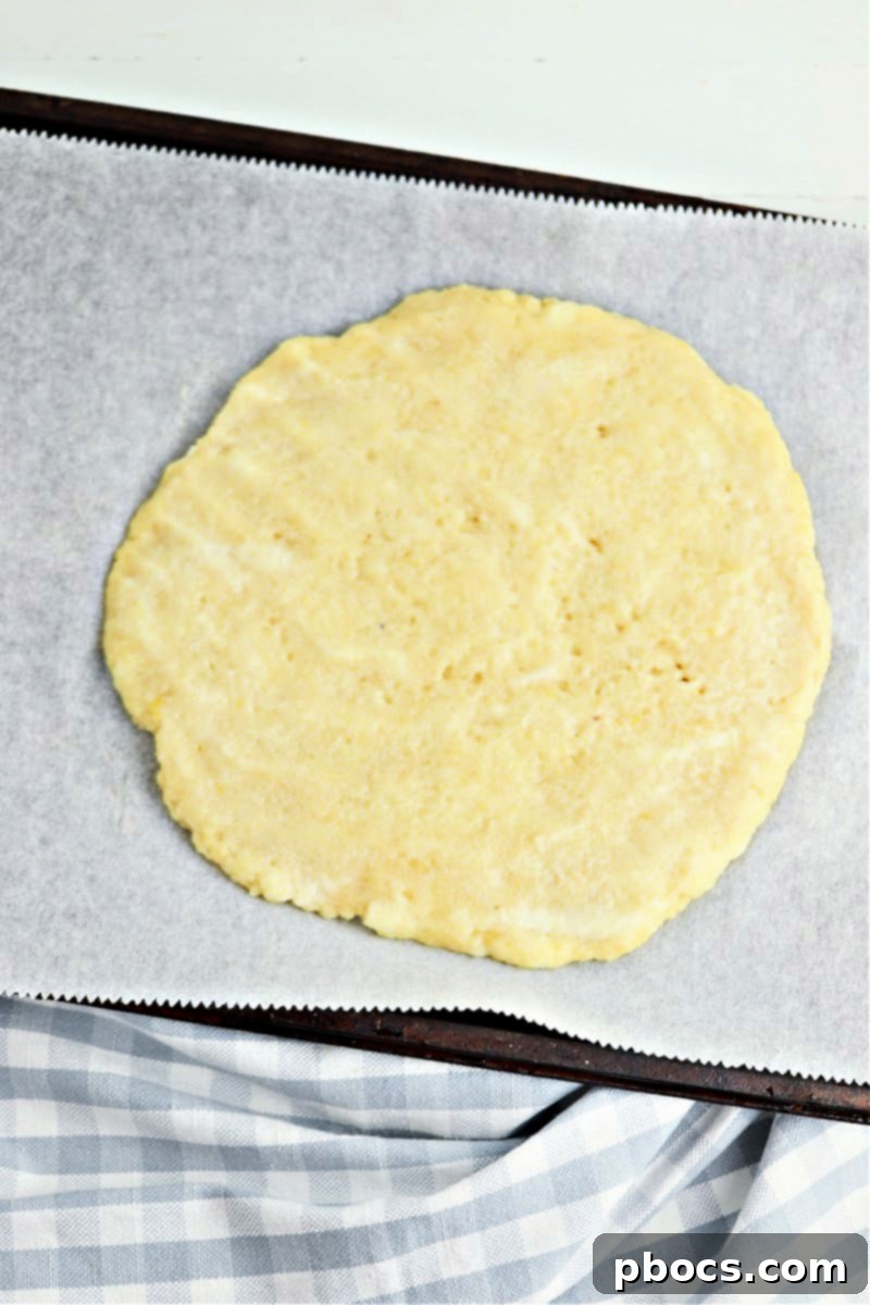 Fathead dough pressed into a pizza crust shape on parchment paper.