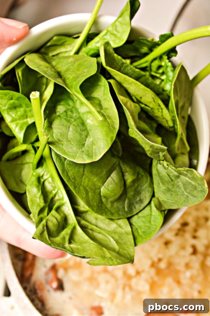 Spinach, coconut milk, and cauliflower rice added to the simmering soup