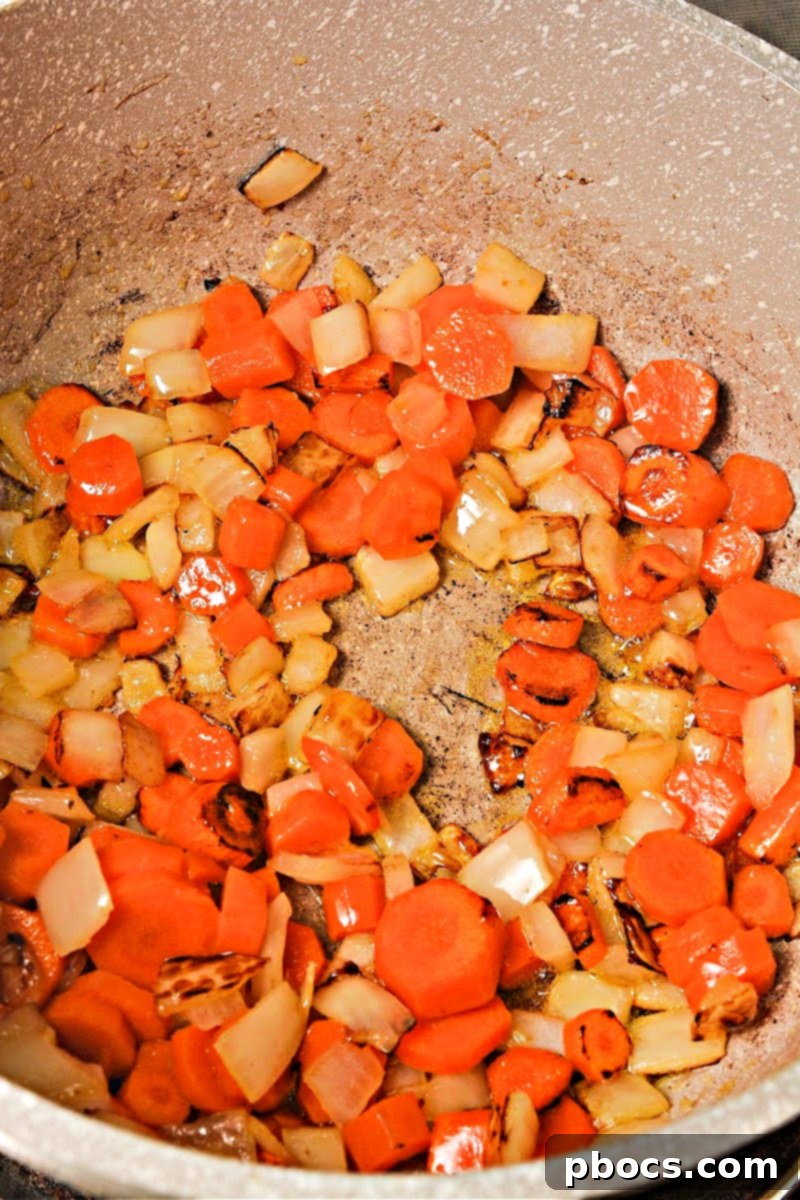 Carrots and onions sautéing in a pot