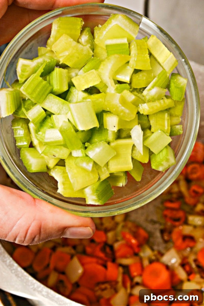 Adding butternut squash, celery, and mushrooms to the pot