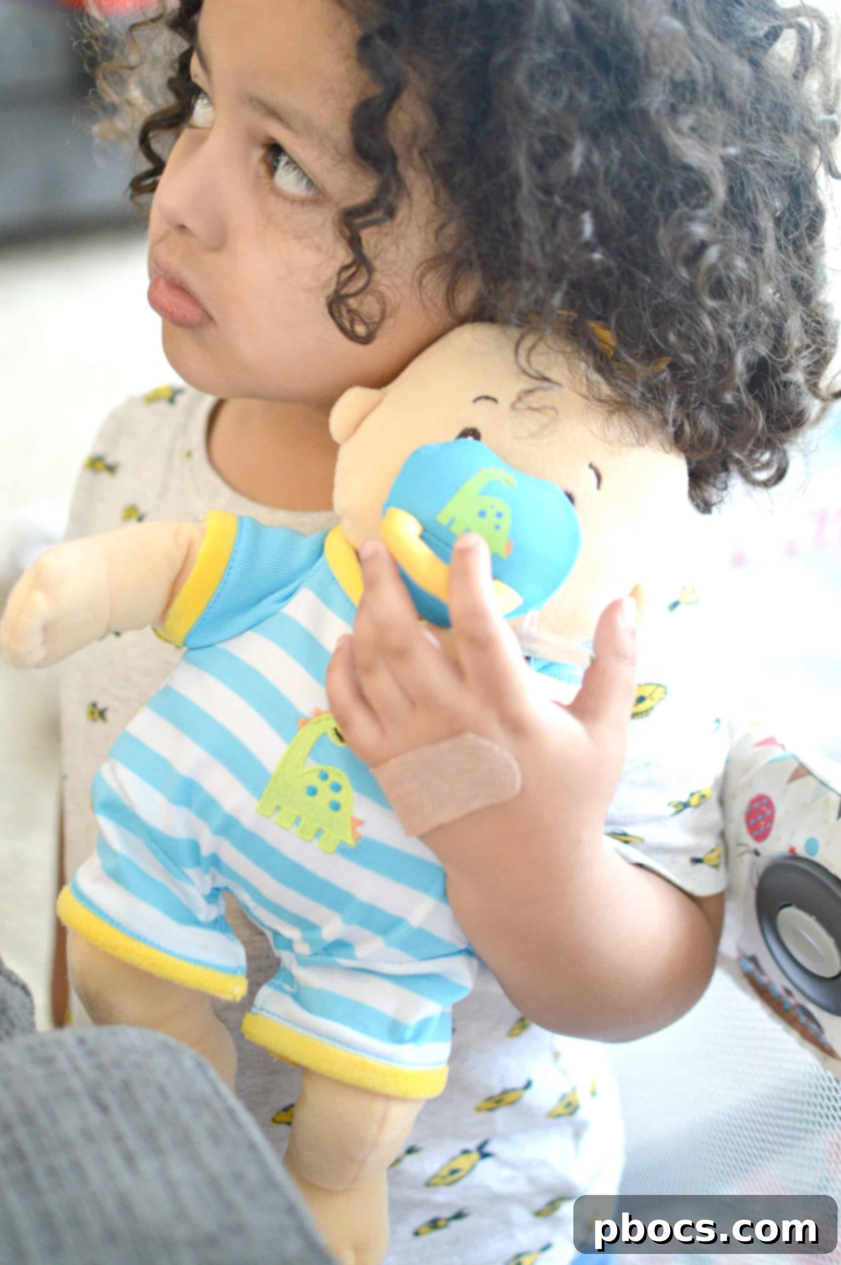 Child interacting playfully with a collection of dolls and soft toys.