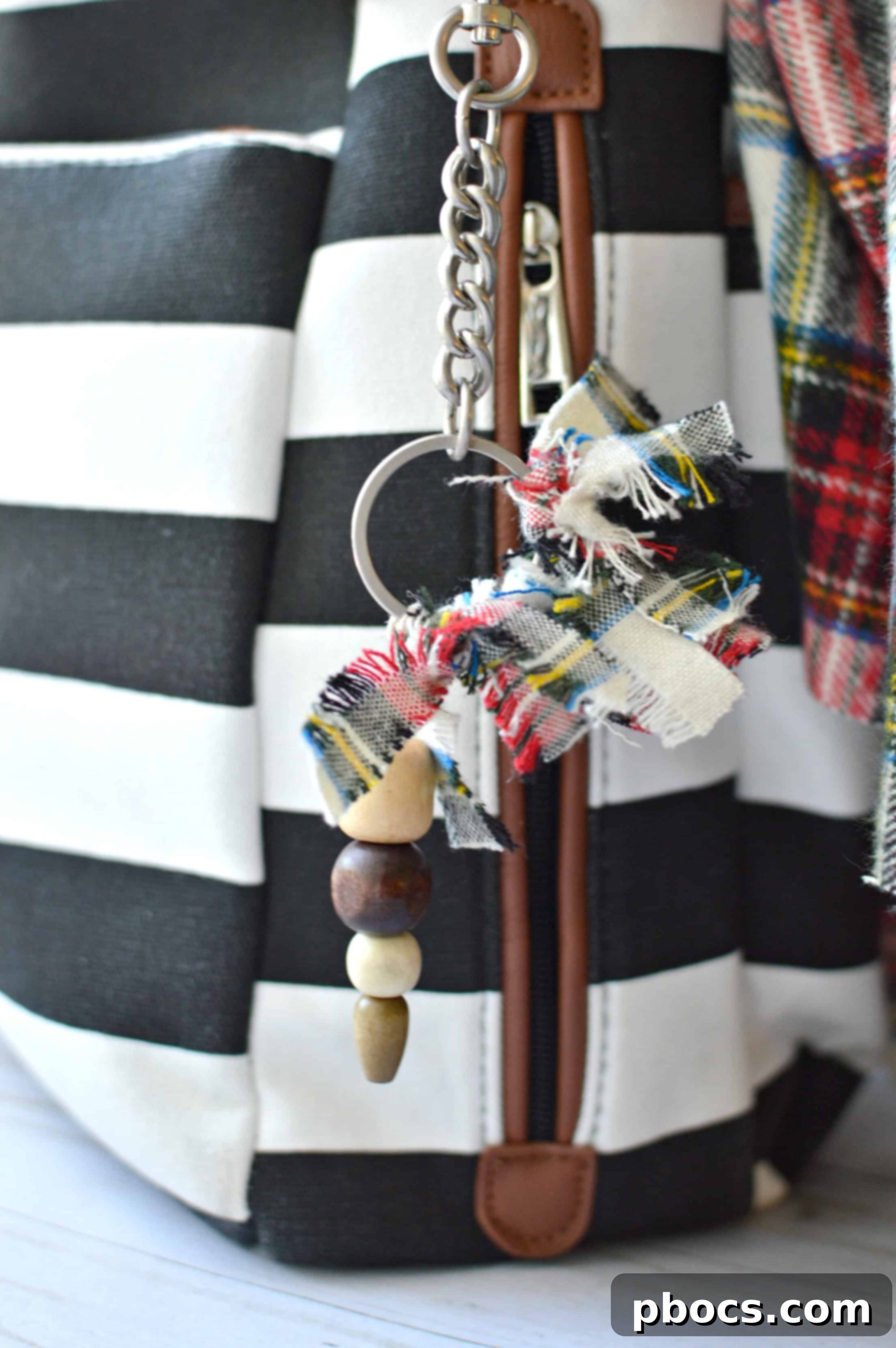 Two DIY rag and wooden bead keychains hanging from a purse, showing their versatility.