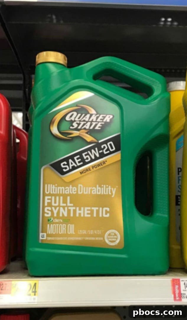 Close-up of Quaker State motor oil bottle being poured into a car engine.