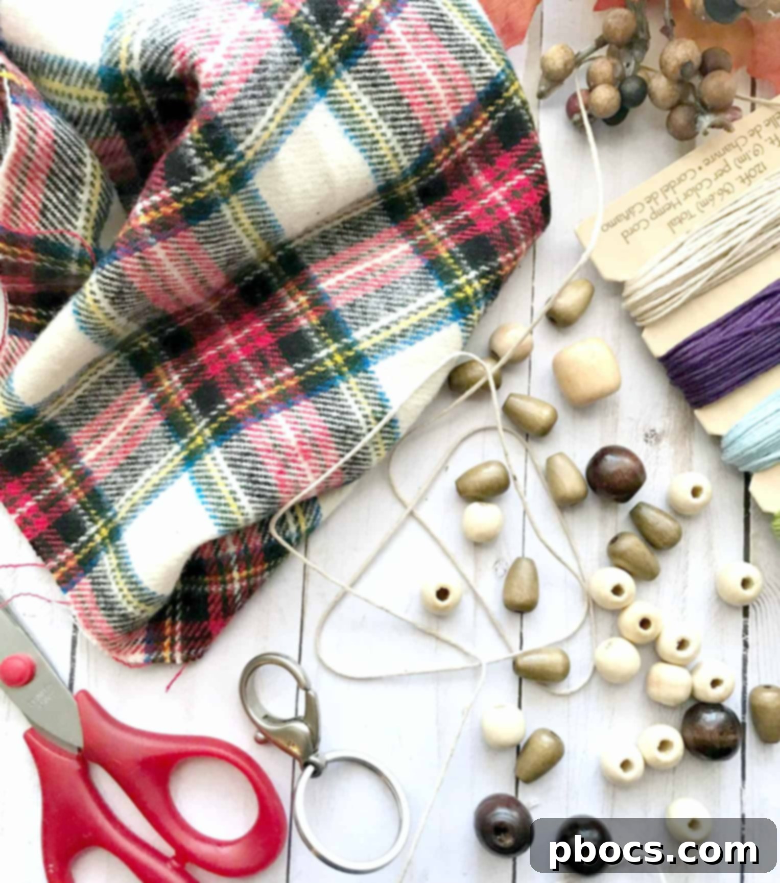 A flat lay of supplies for DIY rag and wooden beads keychain: a keychain ring, fabric scraps, string, and wooden beads.